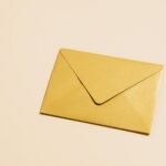 A sleek gold envelope placed on a vibrant yellow background, perfect for postal themes.